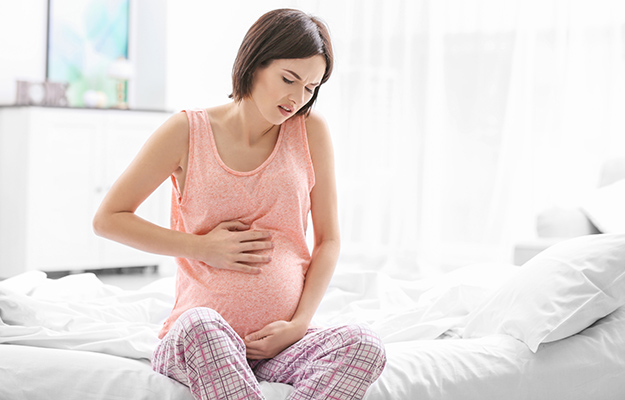 young pregnant woman in bedroom experiencing pain in her belly | Background and Study Overview | Fertility Linked to Biological Age