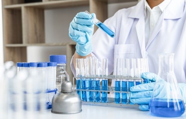 A Scientist is holding test tube with blue liquid inside | Epigenetic Modifications -- Can Scientists Turn Off SARS-Cov-2?