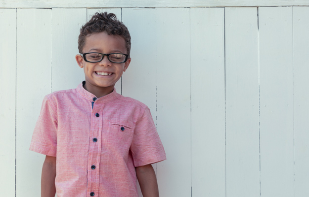 Latinx boy smiling on fence background | Psychological Stress and Social Environment May Influence Epigenetic Aging in Latinx Immigrants | relevant picture
