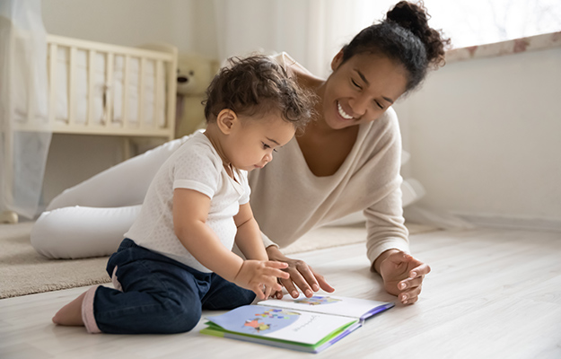 African American mom reading book with her child | Oxytocin System and Social Development in Infants Might Be Influenced by Early Caregiving Environment
