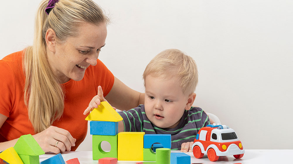Western mom playing cubes with her infant - | - Feature | Oxytocin System and Social Development in Infants Might Be Influenced by Early Caregiving Environment