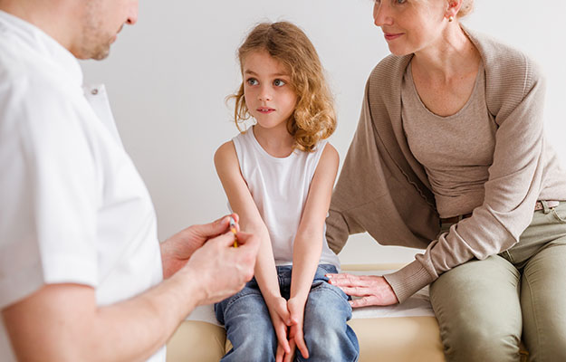 child being consulted by doctor with adult sitting next to | PTSD and Other Psychological Trauma Can Be Hereditary